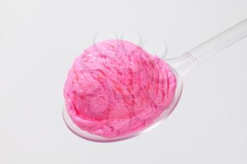 Scoop of pink ice cream on a plastic spoon
