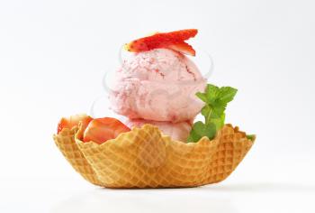 two scoops of strawberry ice cream and fresh strawberries in waffle basket