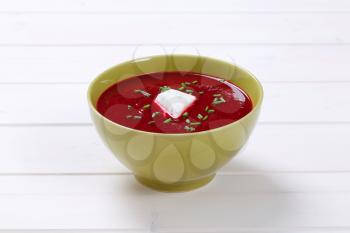 bowl of beetroot cream soup on white wooden background