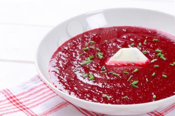 plate of beetroot cream soup on checkered dishtowel - close up