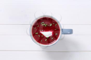 cup of beetroot cream soup on white wooden background