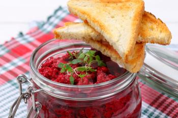 jar of fresh beetroot puree with toast on checkered dishtowel - close up