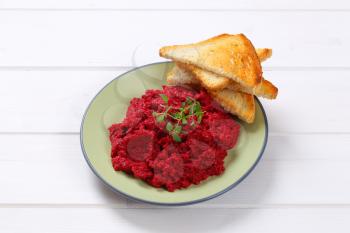 plate of fresh beetroot puree with toast on white wooden background
