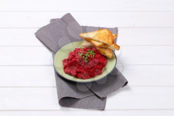 plate of fresh beetroot puree with toast on grey place mat