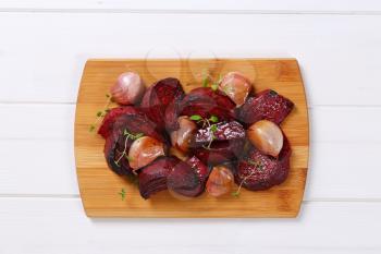 pile of baked beetroot with garlic and thyme on wooden cutting board
