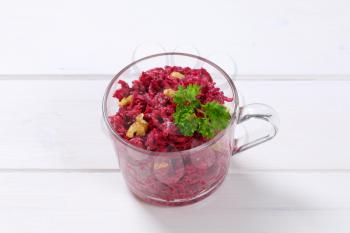 cup of fresh beetroot spread with walnuts on white wooden background