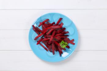 plate of beetroot strips on white wooden background