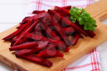 pile of beetroot strips on wooden cutting board - close up