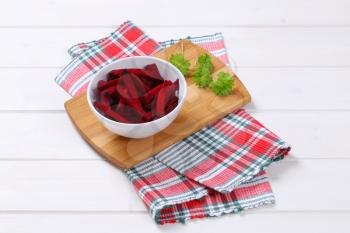 bowl of beetroot strips on wooden cutting board