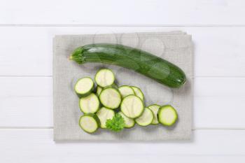 whole and sliced green zucchini on beige place mat