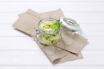 jar of raw zucchini noodles on beige place mat