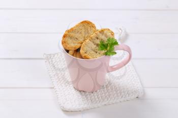 cup of crispy rusks on white table mat