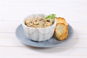 bowl of grated cheese spread with olives and crostini on grey plate