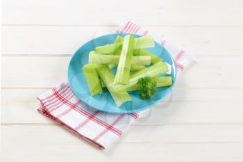 plate of green celery stems on checkered dishtowel