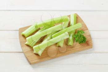 stems of green celery on wooden cutting board