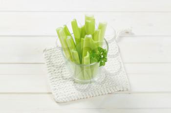 glass of green celery stems on white table mat