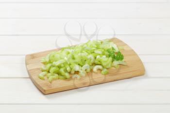 pile of chopped celery stems on wooden cutting board