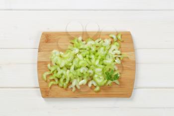pile of chopped celery stems on wooden cutting board