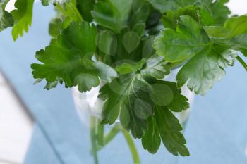glass of fresh parsley leaves on blue place mat - close up