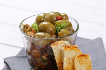 glass of marinated green olives with toast - close up