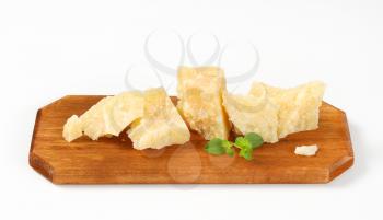 Pieces of Parmesan cheese on wooden cutting board