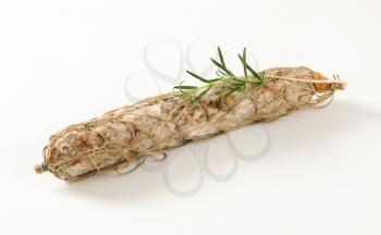 Dry cured pork sausage and rosemary on white background