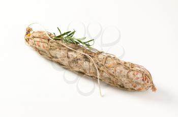 Dry cured pork sausage and rosemary on white background