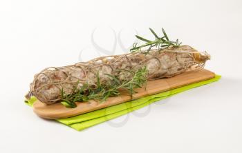 Dry cured pork sausage and rosemary on wooden board