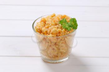 Cooked red lentils in glass on white wooden background