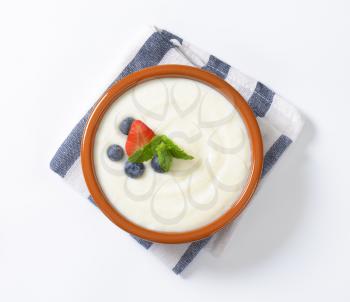 bowl of semolina pudding with fresh fruit on striped napkin