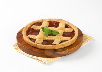 strawberry jam tart with lattice on top on wooden cutting board