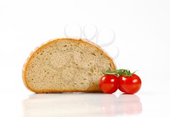 Half a loaf of continental bread and tomatoes on white background