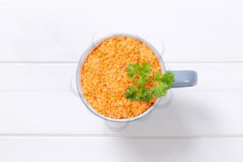 cup of peeled red lentils on white wooden background