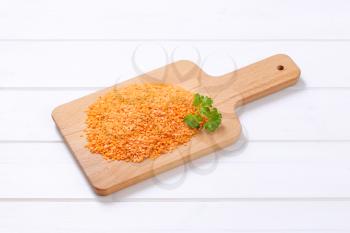pile of peeled red lentils on white wooden background
