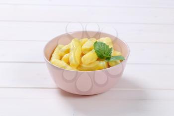 bowl of cooked potato cones or gnocchi on white wooden background