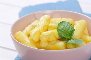bowl of cooked potato cones or gnocchi on blue place mat - close up