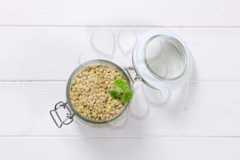 jar of dry brown lentils on white wooden background