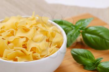 bowl of quadretti - square shaped pasta on wooden cutting board - close up