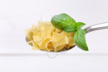 spoon of quadretti - square shaped pasta on white wooden background