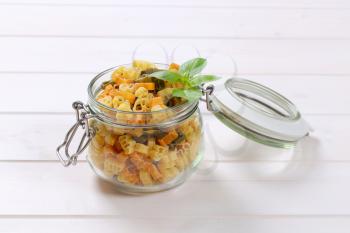jar of raw colored pasta on white wooden background