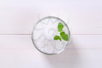 glass of coarse grained sea salt on white wooden background