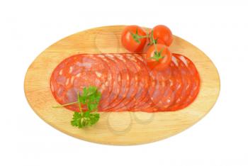 slices of chorizo salami and cherry tomatoes on oval wooden cutting board
