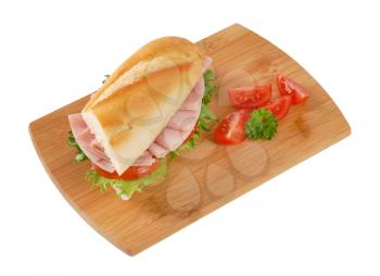 French bread sandwich with ham on wooden cutting board