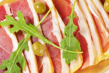 Thin slices of prosciutto crudo and marinated green olives