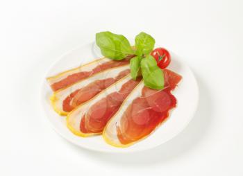 Thin slices of prosciutto crudo on plate