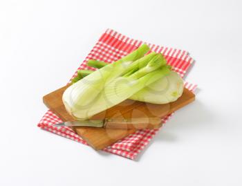 bulbs of fresh fennel and kitchen knife on wooden cutting board