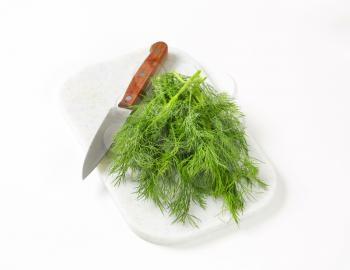 Sprigs of fresh dill weed on white cutting board