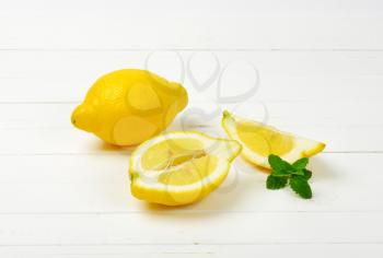 whole and sliced lemons on white wooden background