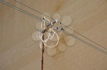 Tangled wires on power pole against a wall