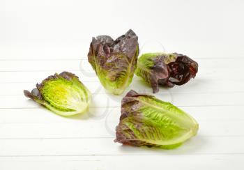 three and half heads of fresh lettuce on white wooden background